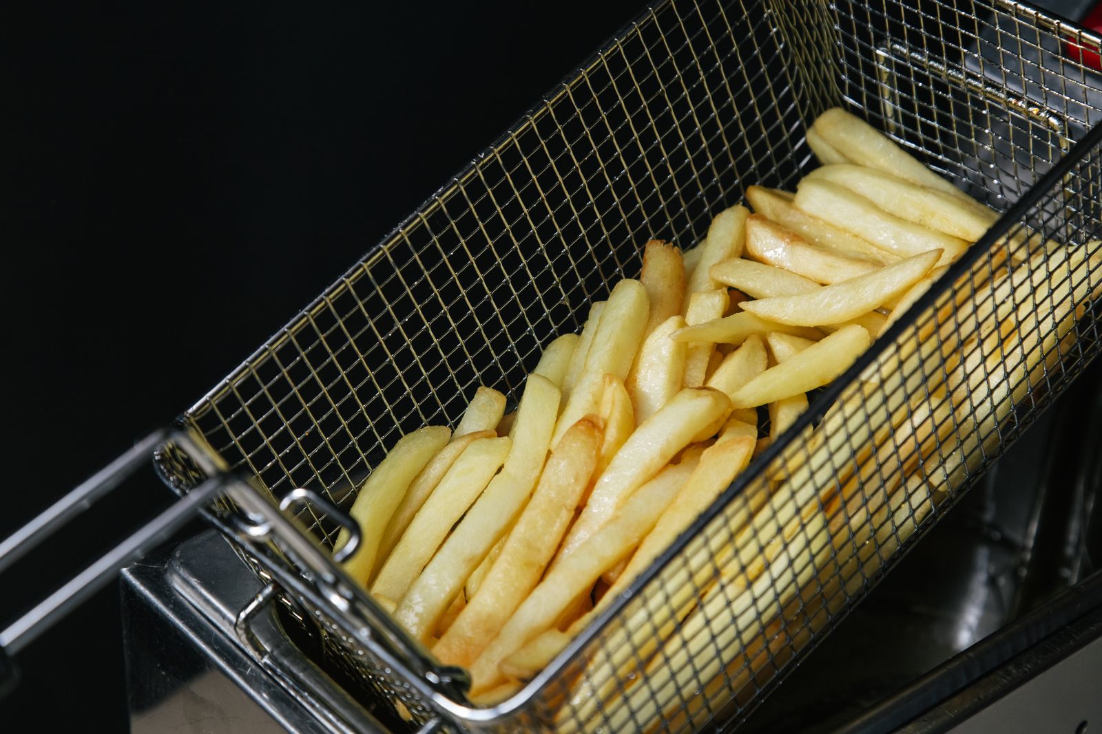 Crispy golden French fries piled in a metal frying basket