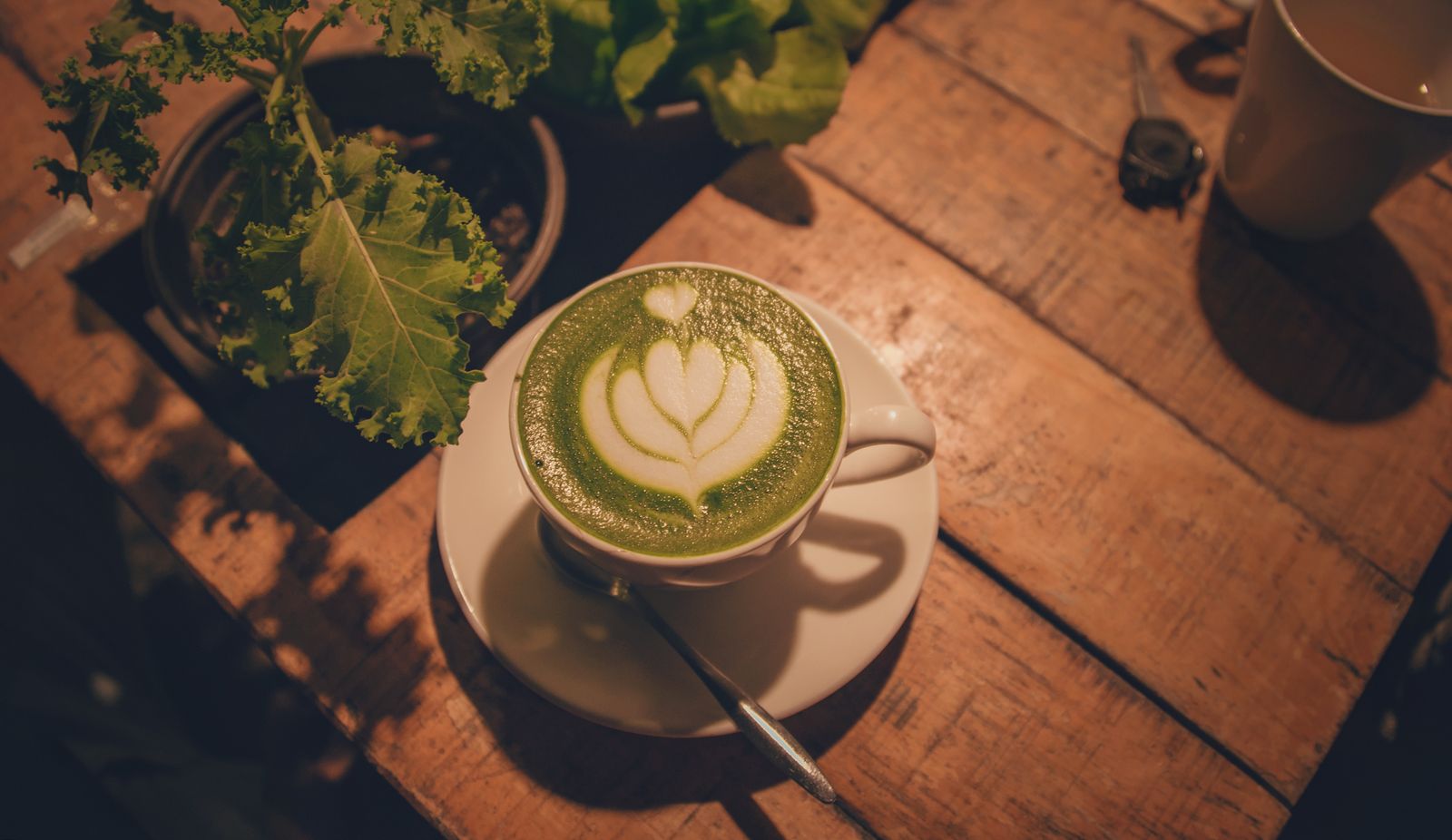 A matcha green tea latte with foam art on a wooden table
