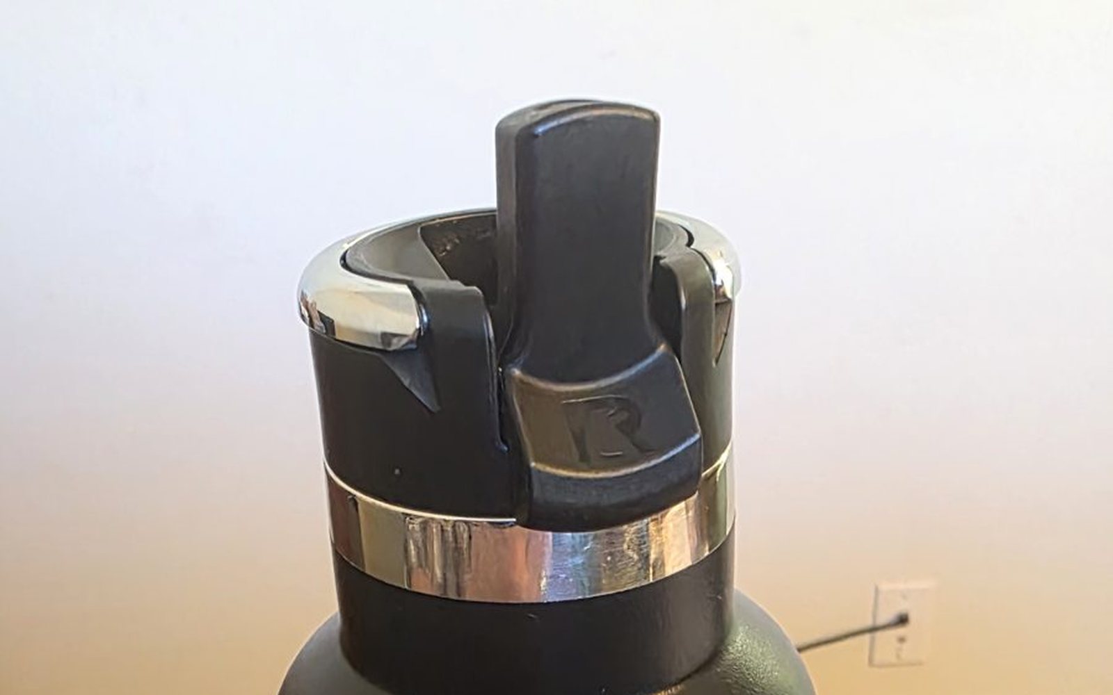 Close-up of the flip-top straw lid on a black RTIC Journey 20 oz bottle, spout flipped up