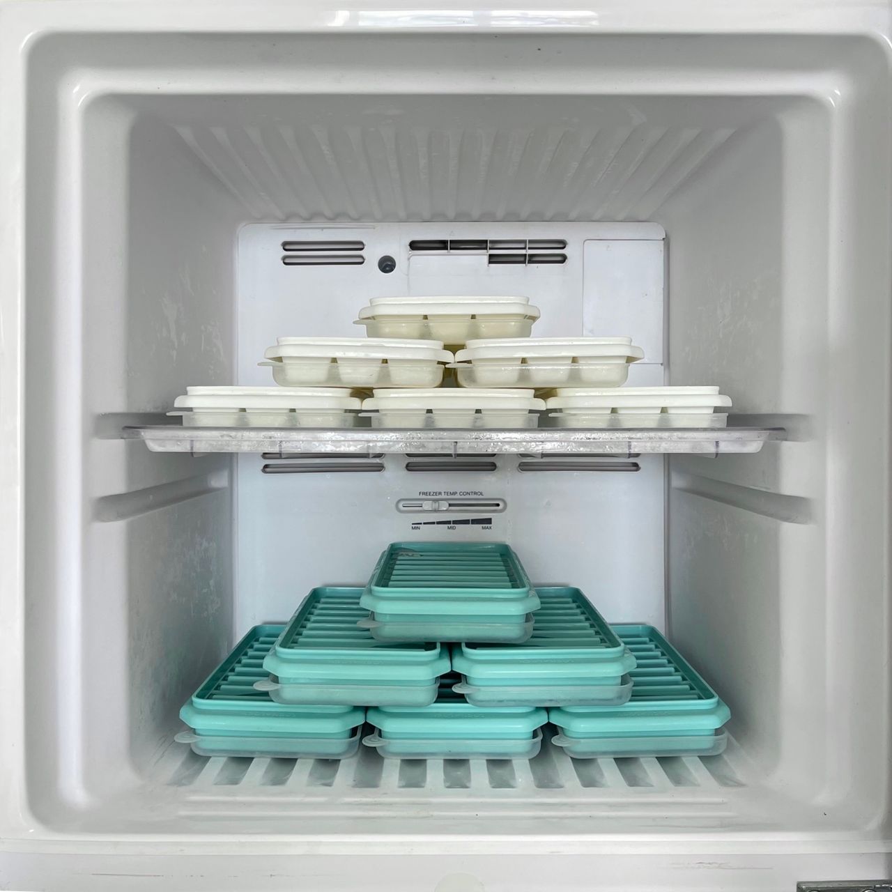 An open freezer with neatly stacked trays on its shelves
