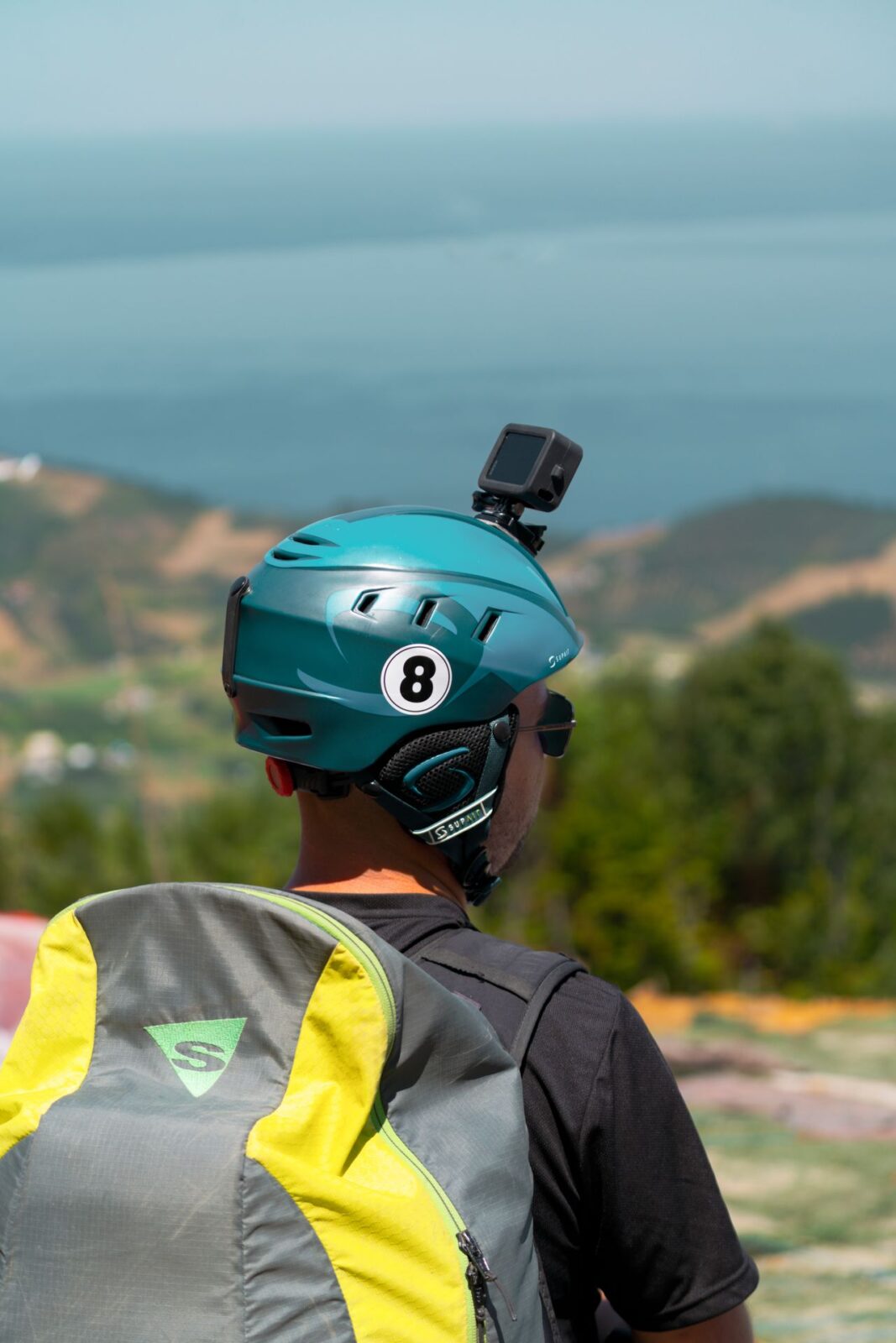 A hiker seen from behind with an action camera mounted on a helmet