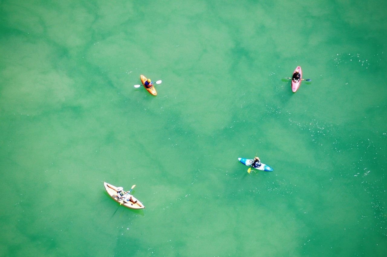 Kayakers paddling on turquoise water, seen from above