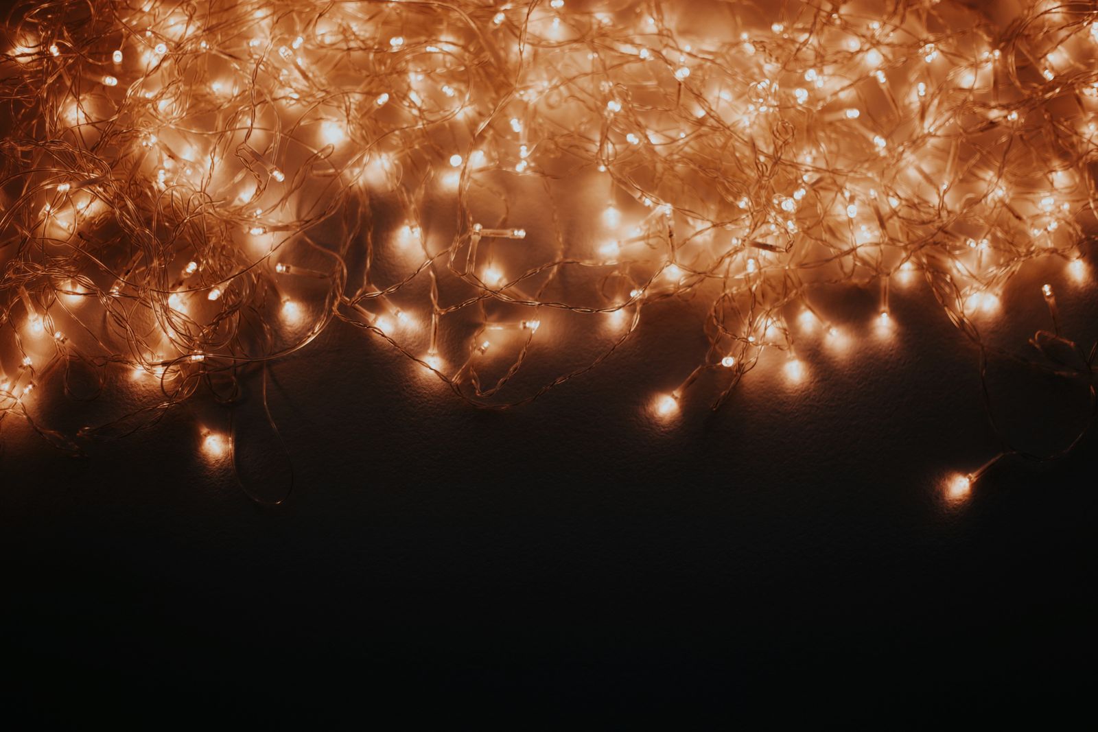A loose tangle of warm-white LED string lights glowing against a dark background