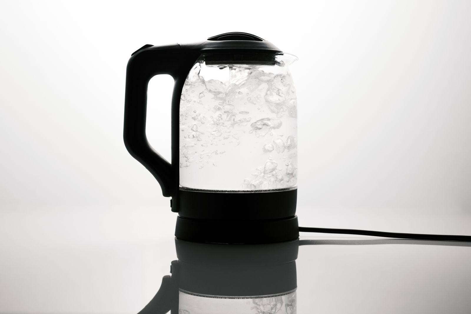Glass electric kettle on its base with water at a rolling boil