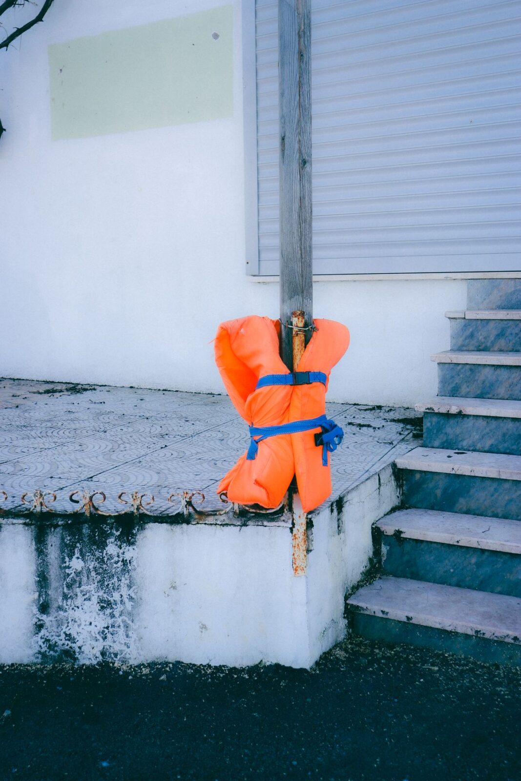 Orange foam life jacket buckled with blue straps around a wooden post