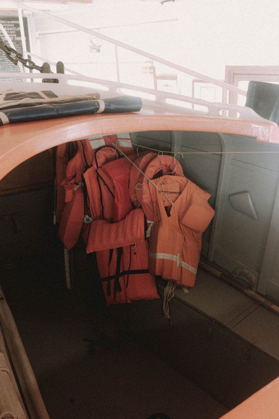 Orange foam life vests hanging on a line inside a small boat