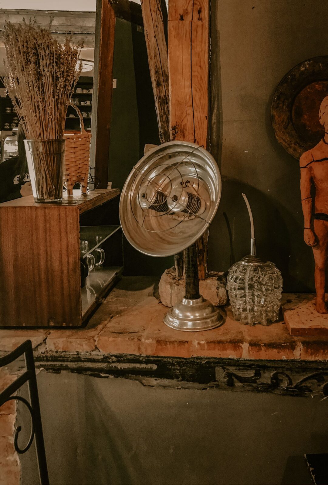 Silver reflector-style electric heater with exposed coils and a wire guard on a brick ledge