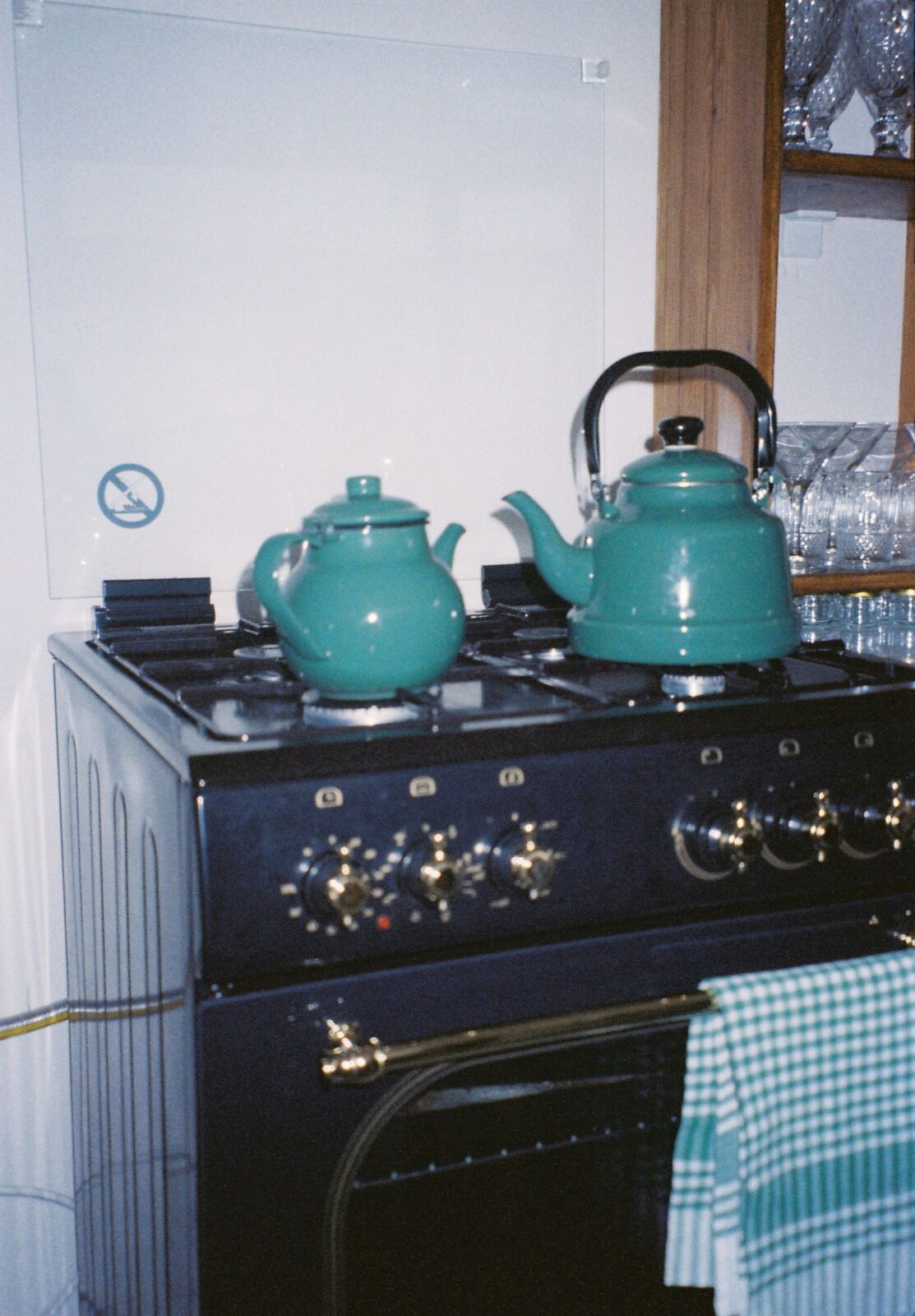 Two teal enamel kettles on the burners of a black gas range
