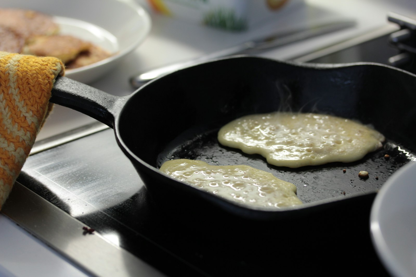 Pancakes cooking in a black cast iron pan on a stovetop