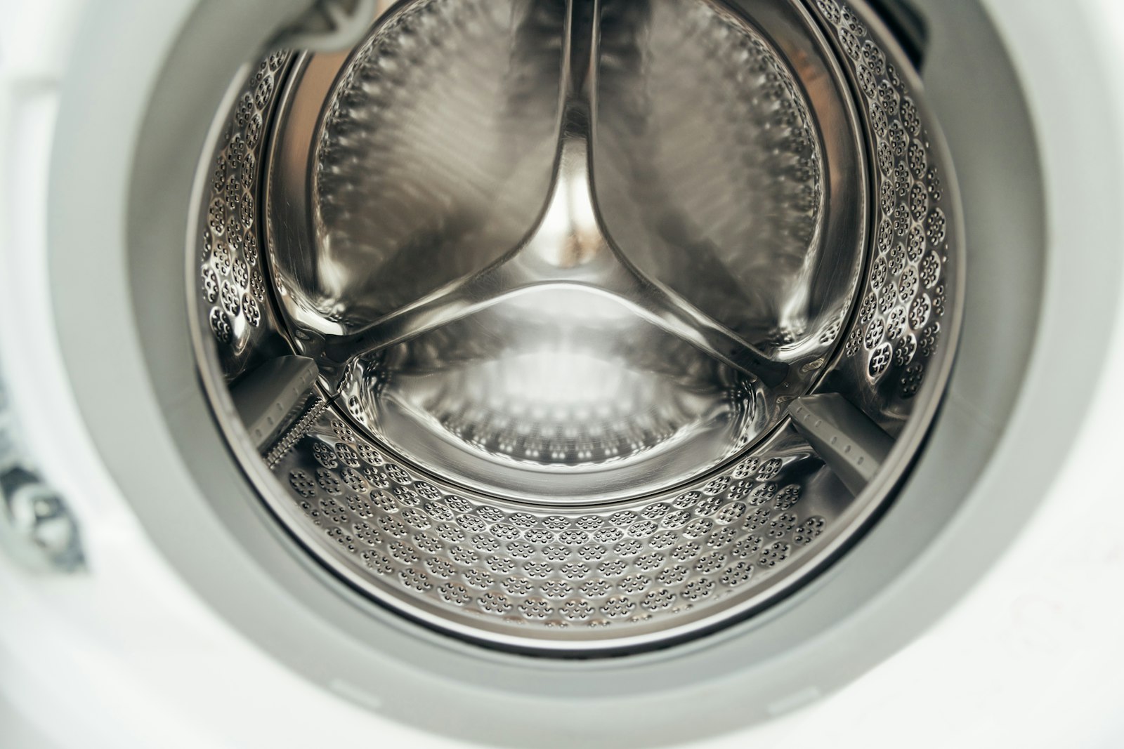 Looking straight into an empty stainless steel washer drum with its lifting paddles