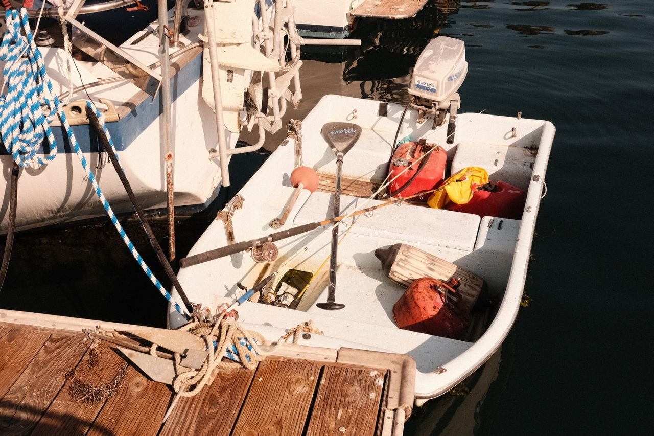 A small open boat moored at a wooden dock with gear aboard