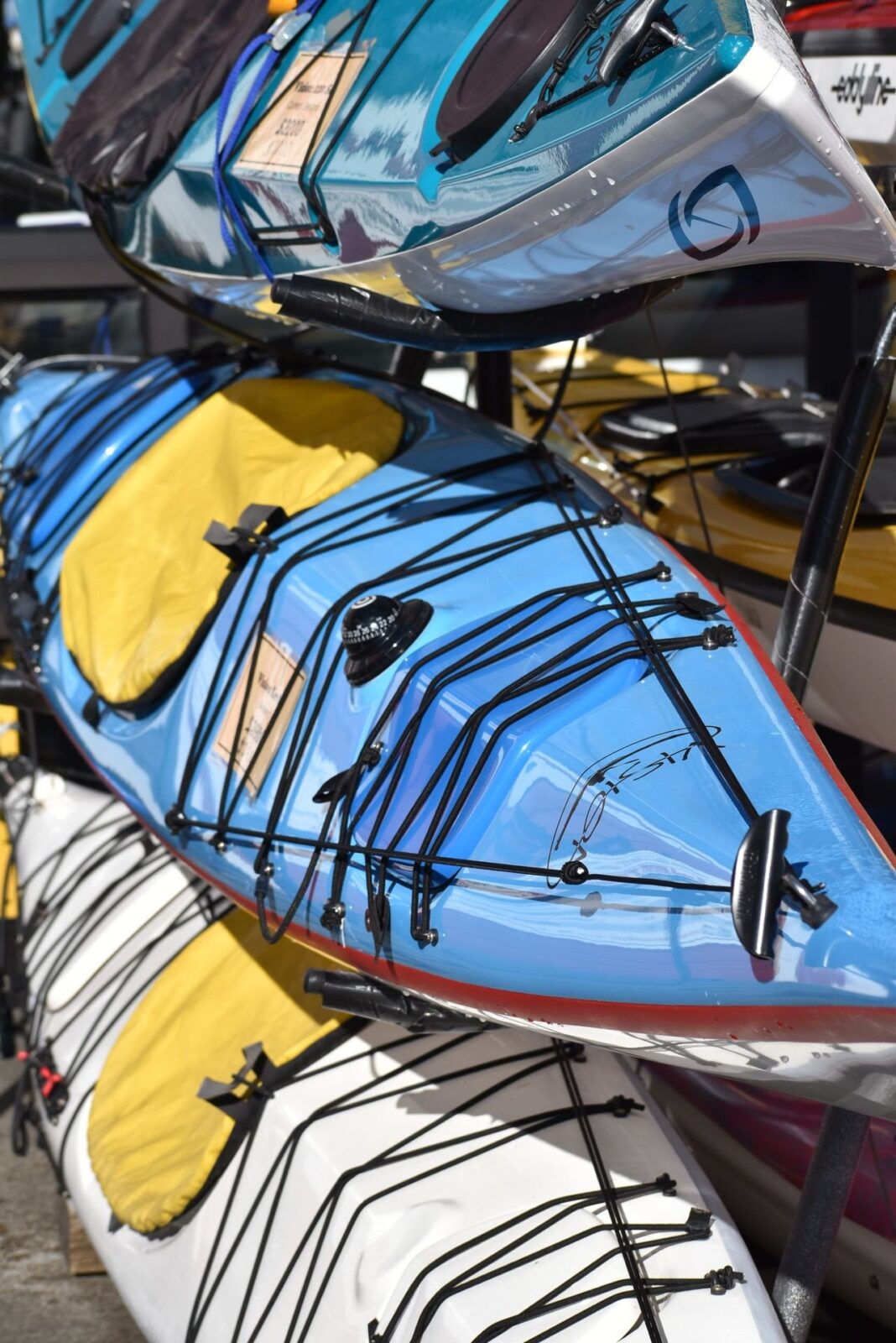 Colorful touring kayaks stacked on a rack outdoors