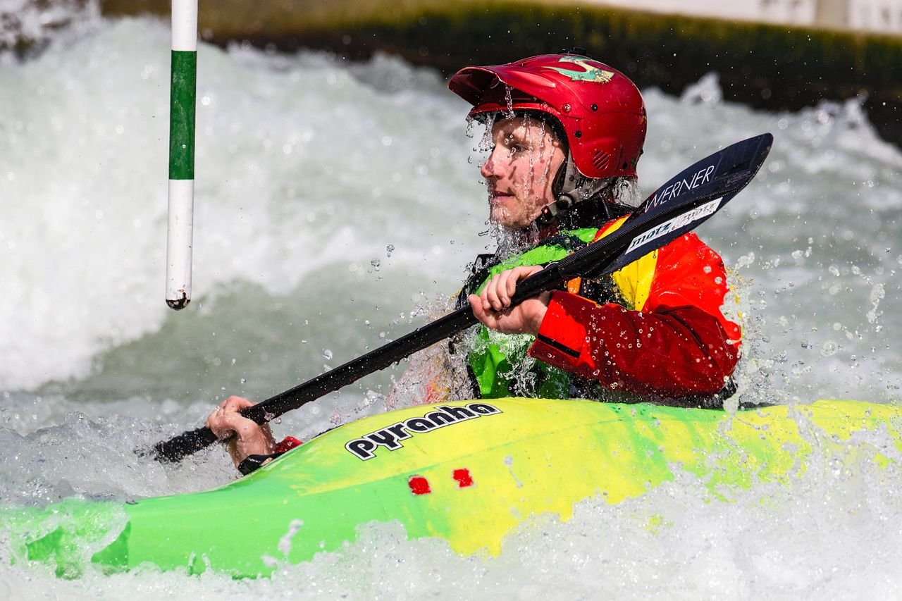 A kayaker in a helmet paddling through whitewater rapids